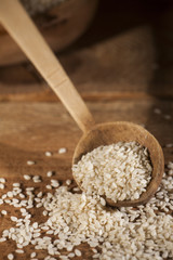 Fresh sesame seeds in a wooden bowl and spoon