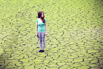 Global concept of worm - cracked scorched earth dune desert landscape dramatic sunset. Girl on the background of an environmental disaster