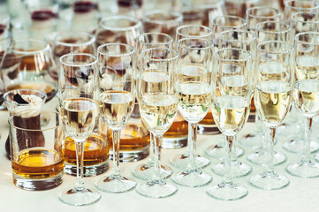 Beautiful row line of different colored alcohol cocktails on a party, Whisky cognac, liquor.