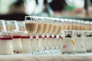 Beautiful row line of different colored alcohol cocktails on a party, Whisky cognac, liquor.