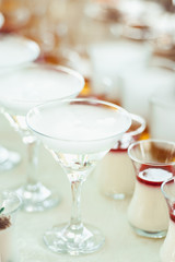 Beautiful row line of different colored alcohol cocktails on a party, Whisky cognac, liquor dry ice.