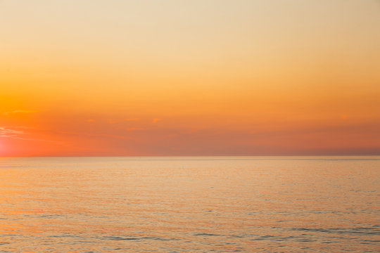 Calm Sea Or Ocean And Yellow Clear Sunset Or Sunrise Sky Background