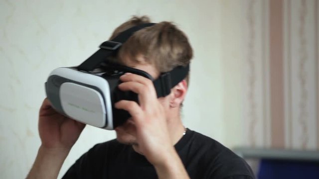 Guy in his room using a vr-box plays a game, close-up.
