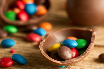 Fototapeta na wymiar Chocolate easter eggs, with multi-colored sweets drops drops on a wooden background. The concept of a holiday and a happy Easter.