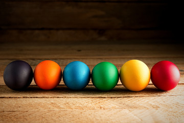 Multicolored easter eggs, on a wooden background, with space for text. The concept of a holiday and a happy Easter.