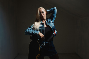 Pretty blonde woman with longboard in dark room
