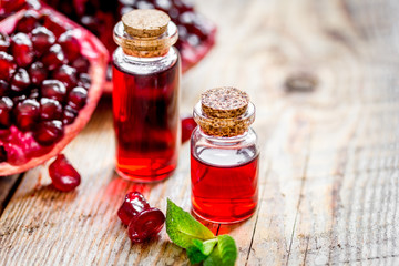 sliced pomegranate and extract in glass on wooden background