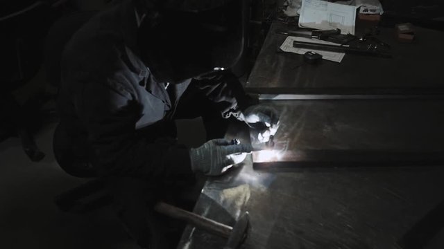 worker with protective mask welding metal on furniture factory