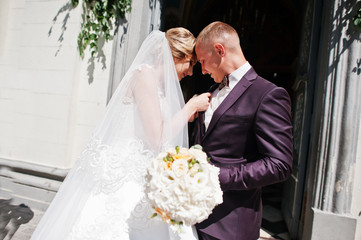 Bride tie buttonhole for her groom at wedding day.
