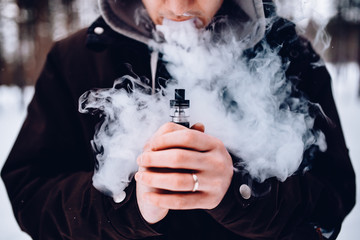 vaping man holding a mod device. cloud of vapor.