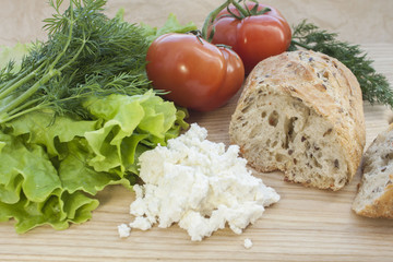 greens, cheese, bread and vegetables on a wooden table
