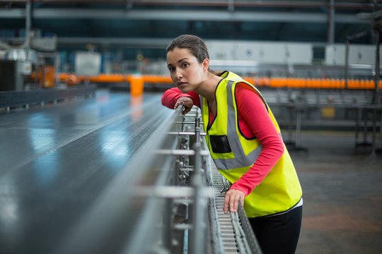Female factory worker checking conveyor belt