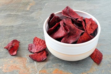 Bowl of healthy beet chips over a slate background
