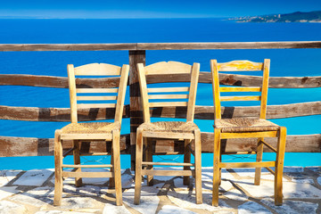 Fototapeta premium Greece romantic composition: three chairs and deep blue sea