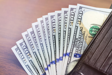 Wallet with hundred dollar banknotes on wooden background, money and finance concept.