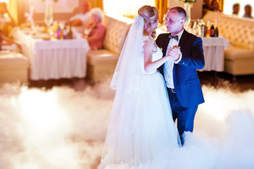 Naklejka premium Amazing first wedding dance with fog smoke at dancefloor and various lights.