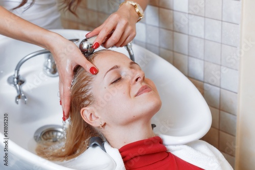 "The hands of the hairdresser wash the hair of a young ...