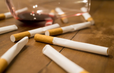 Cigarettes and a glass of red wine on a wooden table