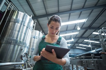 Female factory worker maintaining record on clipboard in factory