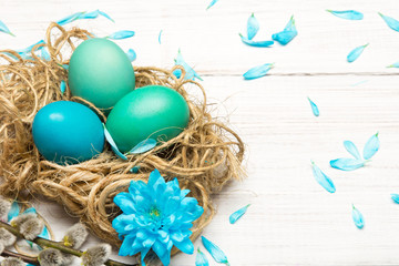 Easter background with eggs, nest and catkins on white wooden background, copy space