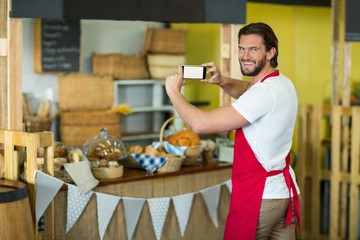 Portrait of bakery staff photographing bakery 