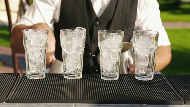 The bartender set the glasses with ice to make the drink