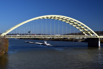 Fototapeta na wymiar Boat on the Ohio river passing under the Big Mac bridge in Cincinnati