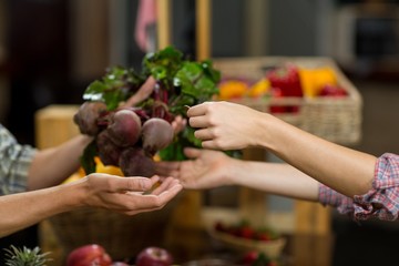 Woman buying beetroot from vendor in the grocery store