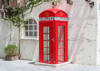 Fototapeta na wymiar Red retro telephone box with white wall
