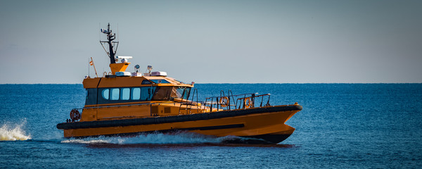 Yellow pilot ship moving at speed from the Baltic sea