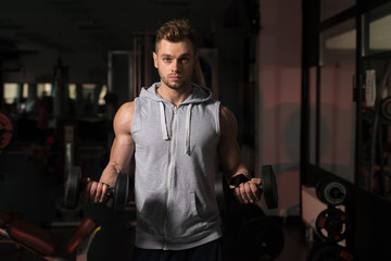 Fototapeta na wymiar Young Man Doing Exercise For Biceps With Dumbbells