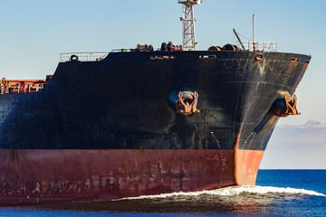 Black cargo ship's bow in still water. Riga, Europe