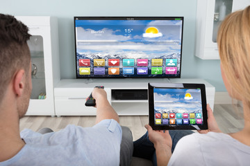 Couple Watching Television Using Digital Tablet
