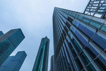 Fototapeta na wymiar Bottom view of modern skyscrapers in business district against blue sky
