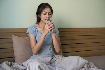 Happy young Asian woman drinking water after waking up ,every thing she does every day in the morning.