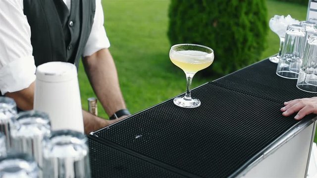 The bartender prepared the drink with lime and gives it to the guest