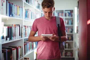 Attentive schoolboy using digital tablet in library