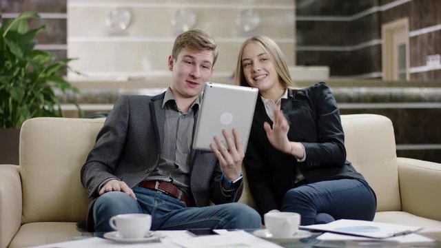 Happy young couple video chatting with family over tablet