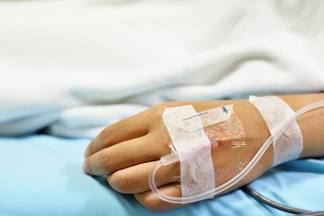 close up of saline solution on hand of women patient in pink clothes lying on the hospital bed
