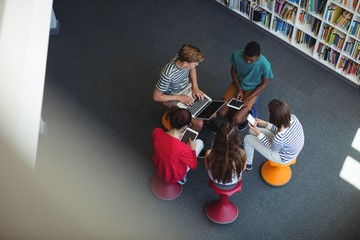 Students using laptop, mobile phone, digital tablet in library