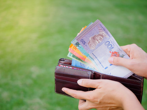 Women Hands taking out money malaysia ringgit from wallet on the green grass field