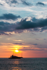 Fototapeta na wymiar The ship sailing in the sunset. The ship in sunset lights sailing in the ocean. Vertical outdoors shot.