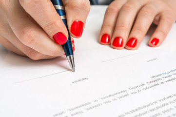 Woman with ballpoint pen signing contract document