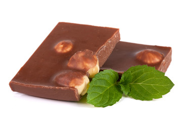 Chocolate with hazelnuts with mint leaves isolated on white background