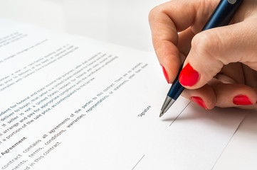 Woman with ballpoint pen signing contract document