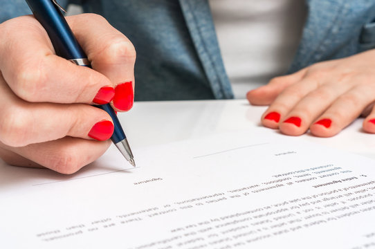 Female hand signing contract to conclude a deal