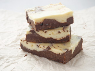 Stack of freshly baked brownie cheesecake. Homemade cake as food background. Marble chocolate brownies arranged upon parchment. Selective focus on the front.