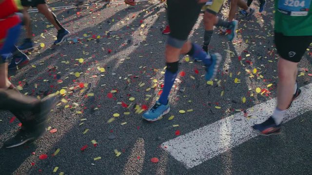 Many legs of unrecognizable multiple joggers pass by seconds after starting their journey of the marathon under the soft and warm barcelona sun, wear athletic gear