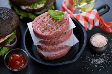 Closeup of a frying pan with fresh uncooked beef burger cutlets, selective focus