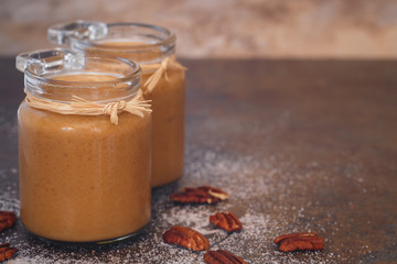Caramel sauces in a preserving jar with pecan nuts next to it